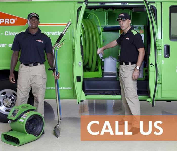 Two SERVPRO technicians in front on a van with drying equipment.