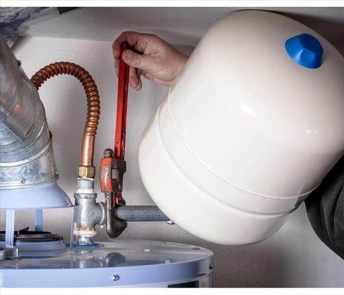 Plumber installs a compression tank on a hot water heater